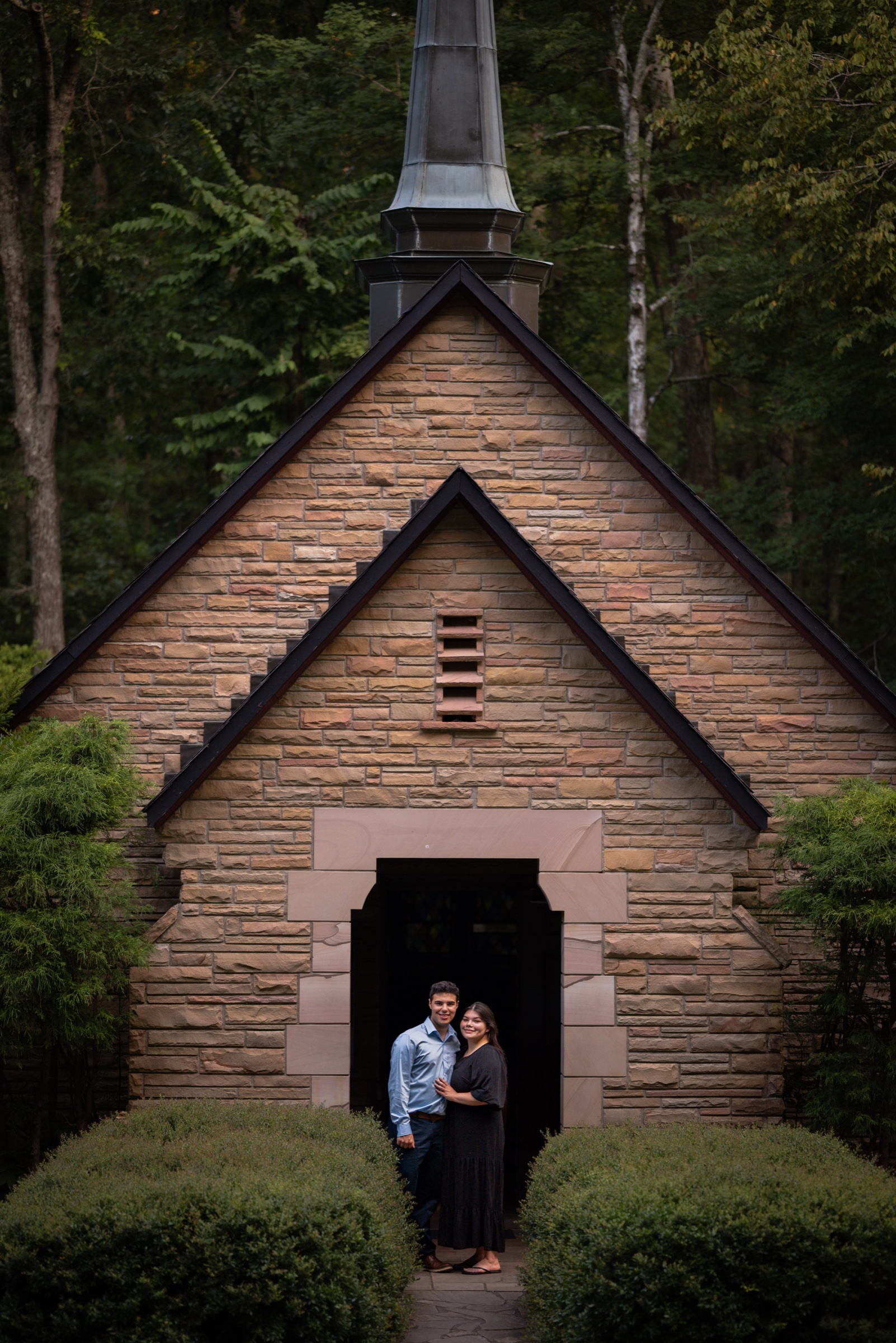 Couple standing in the doorway of a woodland stone chapel