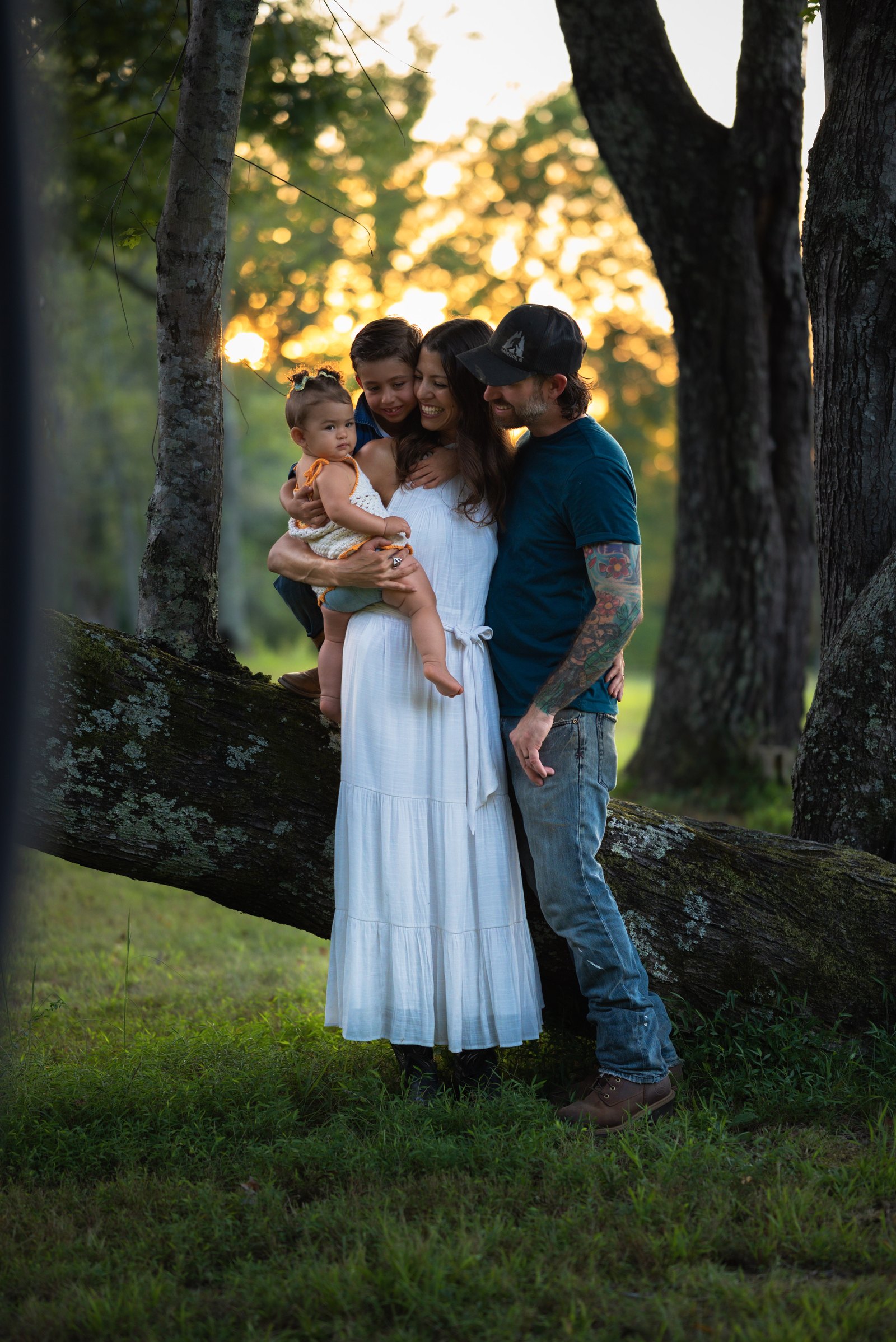 Family of four gathered together beside a fallen tree at sunset