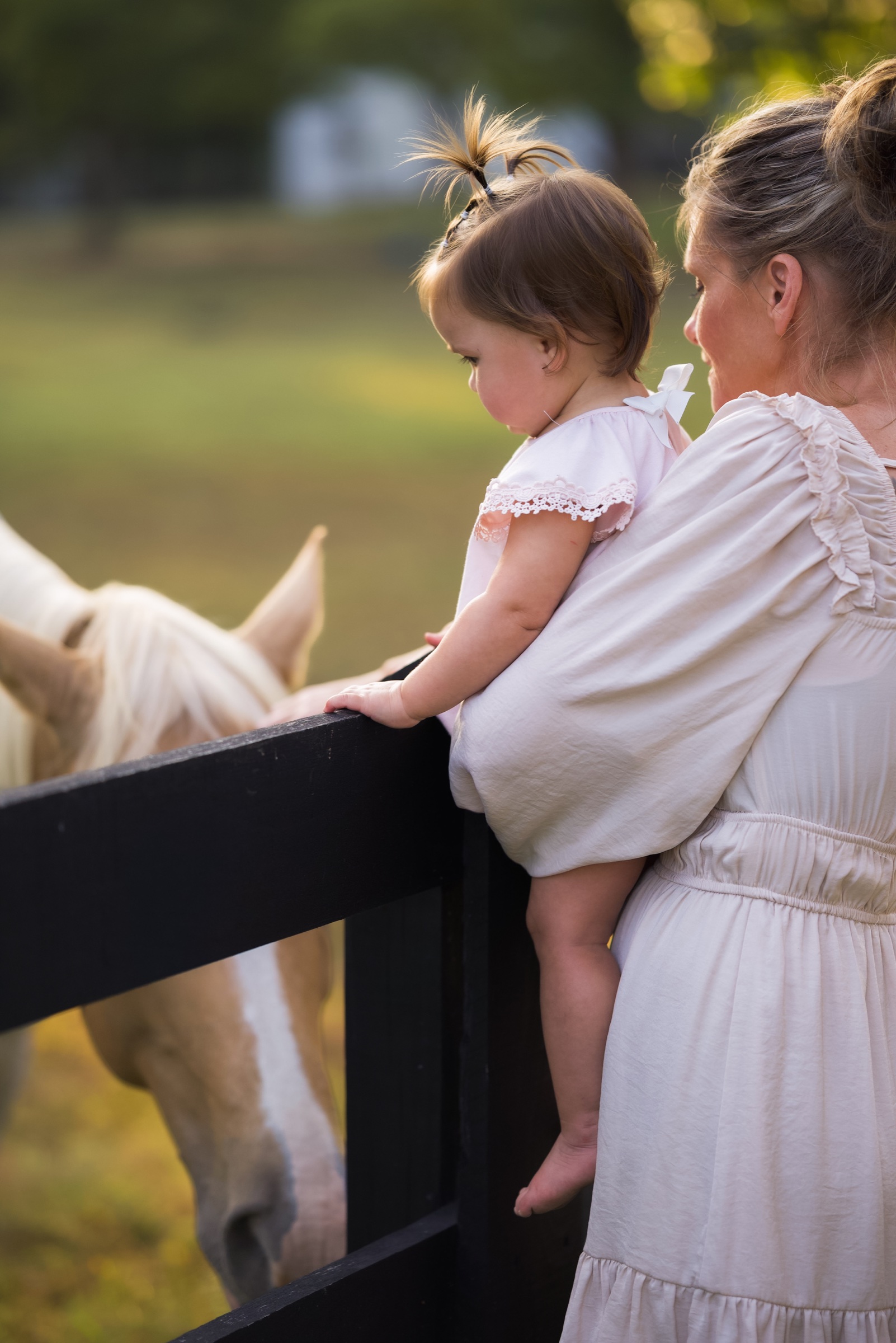 Mother and young daughter sharing a quiet moment beside a horse
