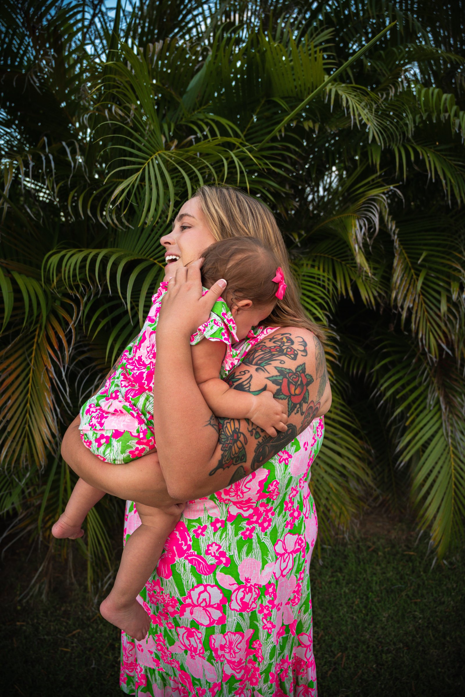Shyanna holding Emmy close in front of tropical palms