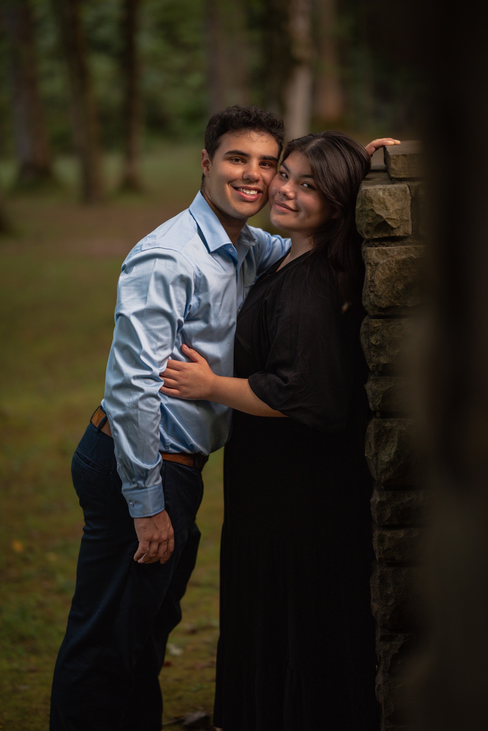 Couple embracing beside a stone wall in the woods