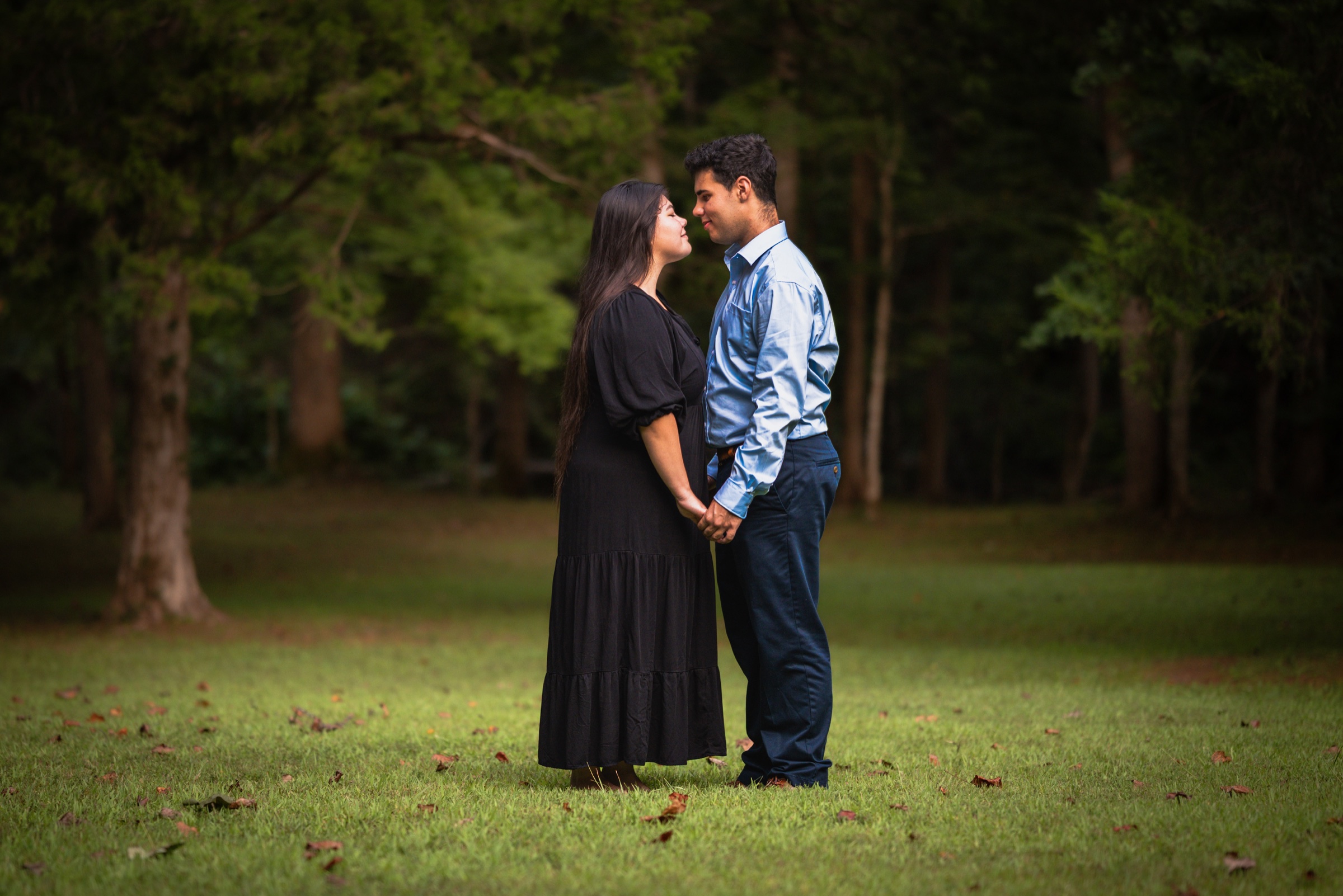 Couple standing together in a green woodland clearing